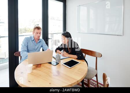 Software developers and project manager discussing prototype on new mobile application on laptop screen Stock Photo