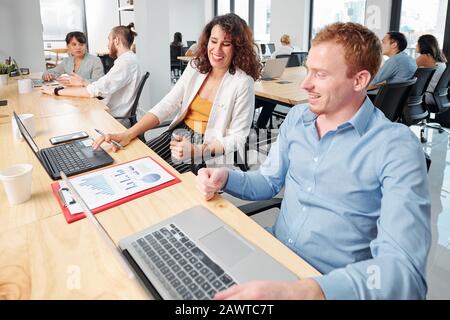 Cheerful colleagues discussing financial report for the business project they are working on Stock Photo