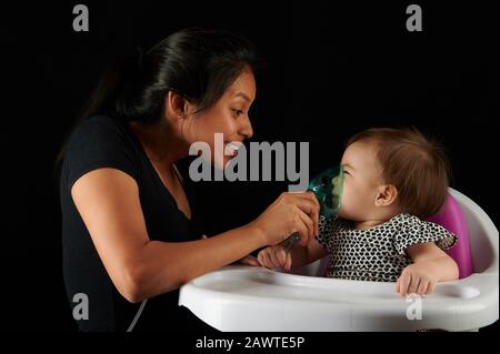 Child breath therapy theme. Young woman help baby with bronchitis Stock Photo