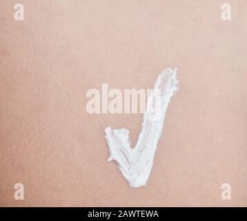 Keeping perfect human skin theme. Tick sign from white skin cream close up Stock Photo