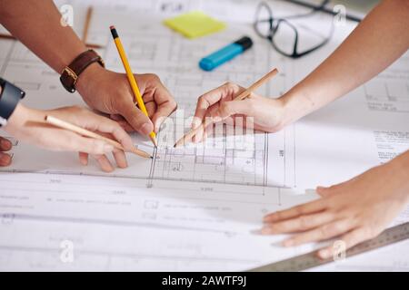 Team of designers and architects discussing project of new house and where to put furniture and decor Stock Photo
