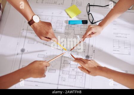 Hands of construction engineers and architects pointing at construction plan Stock Photo