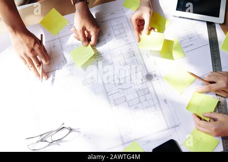 Team of architects planning work and sticking notes on construction plan of new building Stock Photo