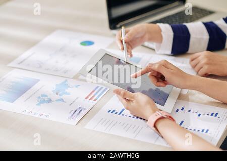 Female financial analysts discussing information on digital tablet when working on annual report Stock Photo