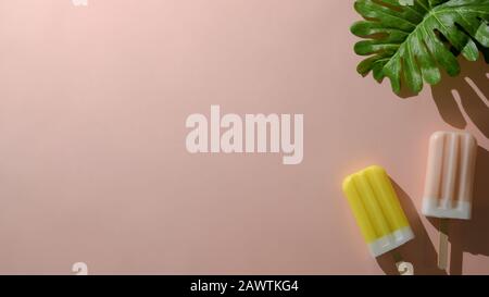 Overhead shot of strawberry and lemon flavour popsicles, summer minimal concept on pink background Stock Photo