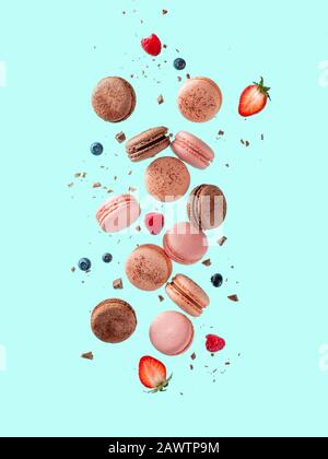 Fly french macarons. Levitate composition with different types colorful macaroons in motion falling or flying on bright blue background Stock Photo