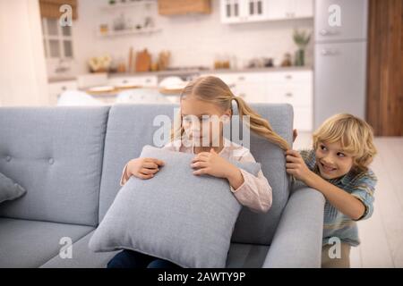 Boy pulling girls ponytail from behind and smiling Stock Photo