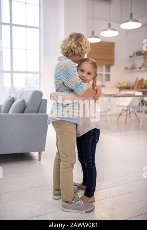 Kids standing in the kitchen, embracing each other Stock Photo