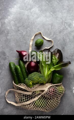 Fresh vegetables and fruits in a string bag on a concrete background. The concept of environmental protection and healthy nutrition, top view Stock Photo