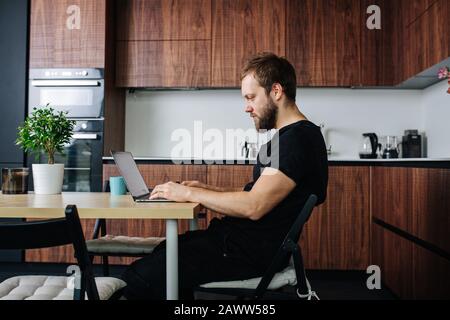 Side view of a man doing freelance work at the dining table. Stock Photo