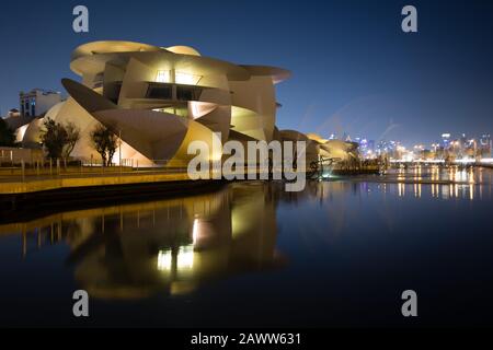 National Museum of Qatar reflected in a small pool outside in Doha.