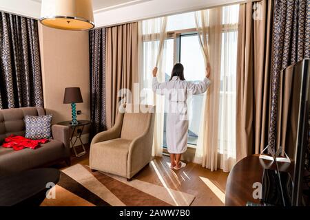 beautiful woman is looking out from window in her modern decorated room