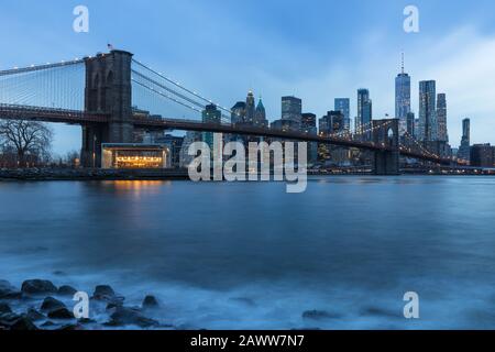 Brooklyn Bridge in Manhattan downtown with Cityscape on a foggy cloudy day at sunset New York USA Stock Photo