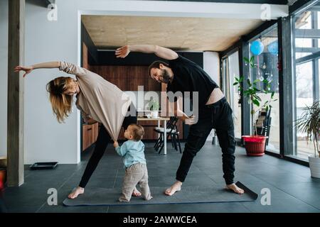 Mother and father doing morning exercises while spending time with their child Stock Photo