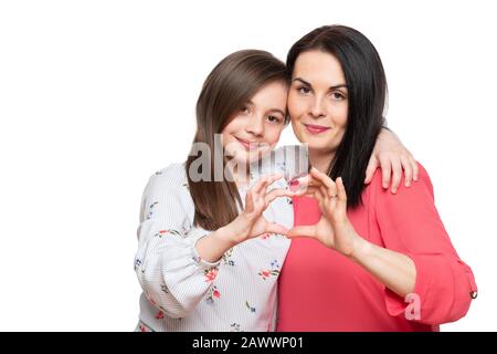 Cute girl and her mother making together heart shape hand gesture. Family love, care and support. Mom and daughter love connection concept. Stock Photo