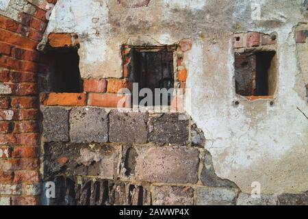 Small windows in red brick wall of old ruined building Stock Photo