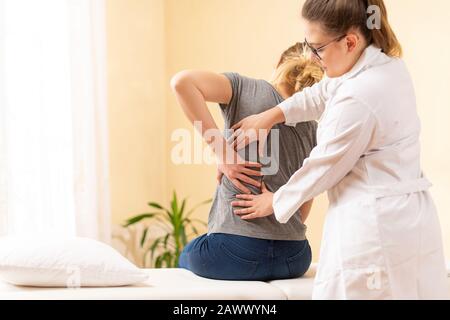Female physiotherapist or a chiropractor examining patients back. Physiotherapy, rehabilitation concept. Stock Photo