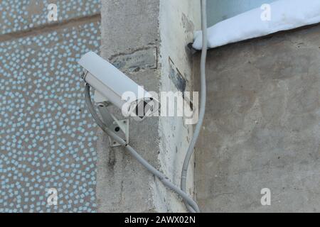 Surveillance camera mounted on tiled wall of house. Security concept, tracking system, monitoring and control. Stock photo for web and print with empty space for text. Stock Photo