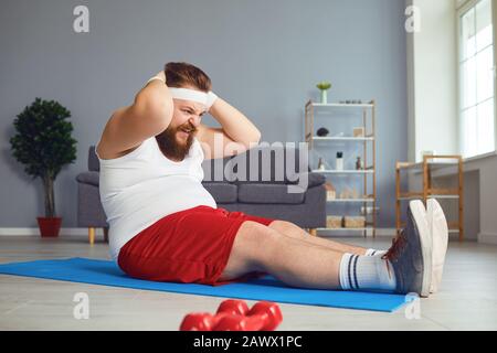 Funny fat man doing exercises in the room. Stock Photo