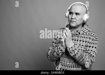 Portrait of young bald Asian man listening to music Stock Photo