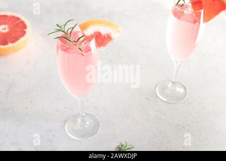 Mimosa cocktail with Champagne, Grapefruit and Rosemary in flute glasses, close up. Mocktail, Mimosa sparkling citrus drink. Stock Photo