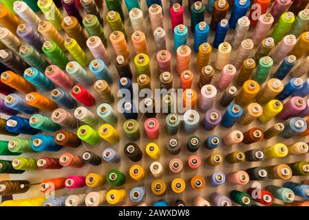 A lot of sewing thread in different colors, sewing thread sorted on a wall Stock Photo