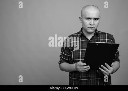 Young bald Asian businessman against gray background Stock Photo