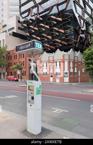A modern high tech electronic parking meter in Spring Street, Melbourne contrasts with the historic Elms Hotel and Mission buildings across the road Stock Photo