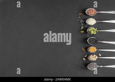 Various Seeds on black background. Assortment, set of  sesame seeds, flax seed, sunflower seeds, pumpkin seed, chia, hemp seeds in spoons, healthy foo Stock Photo