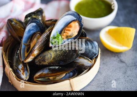 Mussels with herbs lemon on cook steamer food background / Fresh seafood shellfish in the restaurant mussel shell food on bamboo steamer Stock Photo