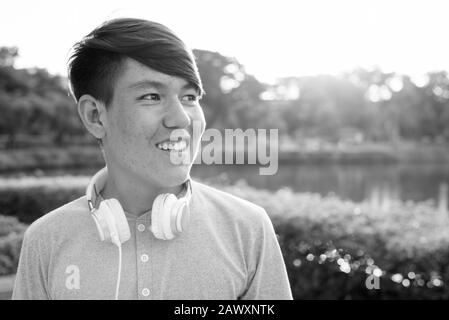Young Asian teenage boy wearing headphones while relaxing at the park Stock Photo