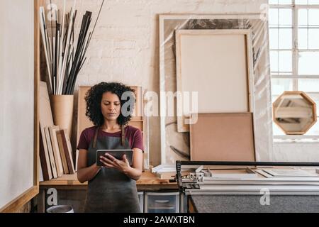 Young woman using a tablet in her framing studio Stock Photo