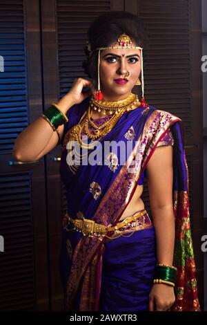 beautiful indian marathi bride in traditional nauvari saree and jewelry looking at camera