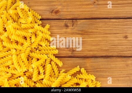 Uncooked dried Eliche pasta spirals on a wood background Stock Photo