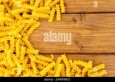 Uncooked dried Eliche pasta spirals on a wood background Stock Photo