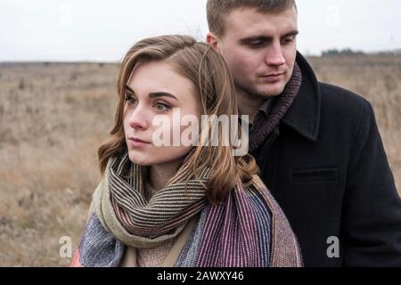 Serious troubled couple standing close together looking away from each other Stock Photo