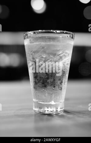 Glass Of Drinking Water Indoors On Table With City Background At Night Stock Photo