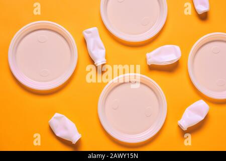 Horizontal from above flat lay shot of white plastic empty plates and bottles lying on orange surface Stock Photo