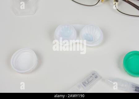 Contact lens case surrounded by various eye care products including glasses, eye drops, and more Stock Photo