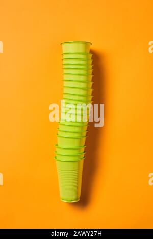 Vertical from above flat lay shot of disposable green plastic cups set on bright orange background Stock Photo