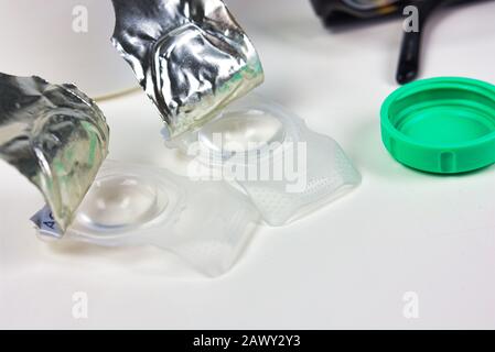 New contacts with freshly opened containers and cap and glasses beside Stock Photo