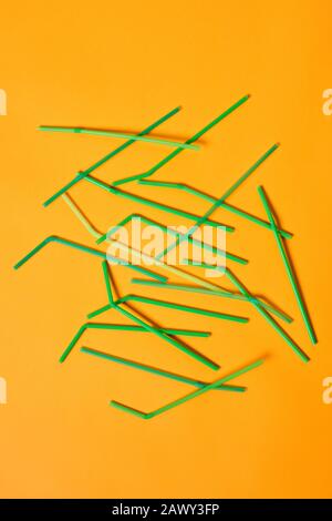 Vertical conceptual flat lay image of disposable plastic drinking straws on bright orange background Stock Photo