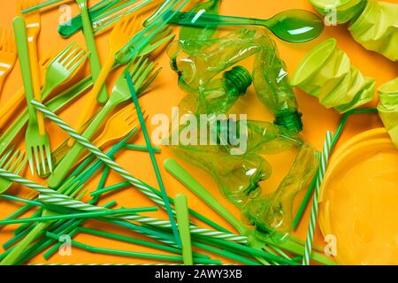 Horizontal flat lay shot of various green plastic litter lying on bright orange surface Stock Photo