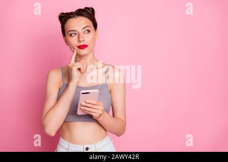 Portrait of minded girl use smartphone want type message think thoughts touch hand chin look copyspace wear stylish clothing isolated over pink color Stock Photo