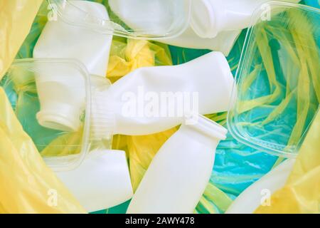 Empty plastic bottles and containers in yellow plastic garbage bag, horizontal flat lay close up shot Stock Photo