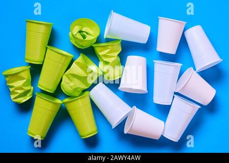 Light green anf white plastic cups on blue background, conceptual flat lay composition shot Stock Photo