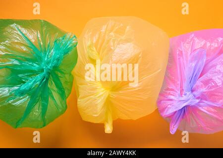 Horizontal from above conceptual shot of three multi-coloured plastic bags full of air on orange background Stock Photo