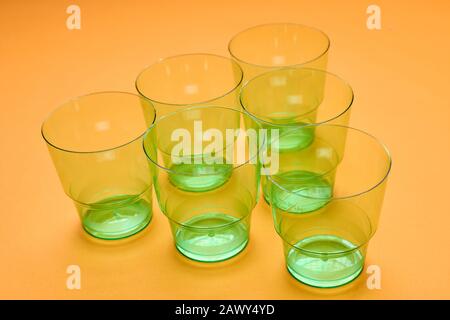 Horizontal high angle shot of six clean transparent green plastic cups on orange surface Stock Photo
