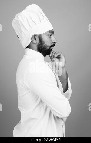Portrait of young handsome bearded Indian man as chef Stock Photo