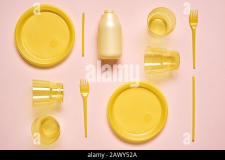 Yellow plastic utensil on pale pink background, horizontal from above flat lay shot Stock Photo